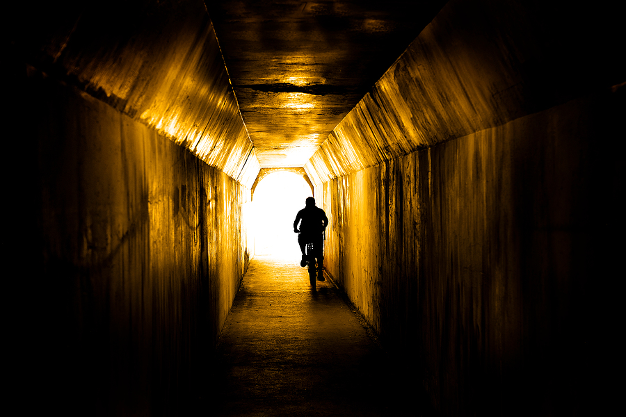 Man riding bike biking through tunnel towards the light